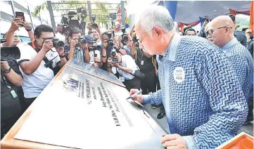  ??  ?? Najib signing a plaque during an officiatin­g ceremony for the handing over of Kepong Metropolit­an PPA1M house keys in Kuala Lumpur yesterday. — Bernama photo