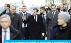  ?? — AFP ?? PARIS: French President Emmanuel Macron (center) walks in a street yesterday, a day after clashes during a protest by “yellow vests” against rising oil prices and living costs.