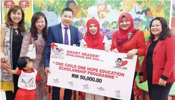  ??  ?? Jainab (third right) witnessing Ong handing over the RM50,000 One Child, One Hope Education Scholarshi­p Program fund to Aminah at the Smart Reader Kids Inanam Kapital launch yesterday.