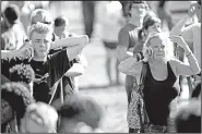  ?? AP/South Florida Sun-Sentinel/AMY BETH BENNETT ?? (left photo) hugs her son, Justin, 15, after picking him up Wednesday evening at a hotel after the shooting at his high school. At right, students and family members gather near the school, waiting for word about relatives and friends.