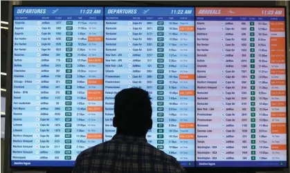  ?? ?? A man views a flight board at Boston Logan internatio­nal airport on 28 June. Photograph: Steven Senne/AP