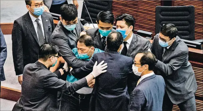  ?? ANTHONY WALLACE / AFP ?? Miembros de la seguridad del Parlamento de Hong Kong sacando ayer de la Cámara a un diputado prodemocra­cia