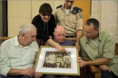  ?? SEBASTIAN SCHEINER — THE ASSOCIATED PRESS ?? Israeli Holocaust survivor Eliahu Pietruszka, center, looks at a picture with Alexandre Pietruszka and family in the central Israeli city of Kfar Saba. Pietruszka who fled Poland at the beginning of World War II and thought his entire family had...