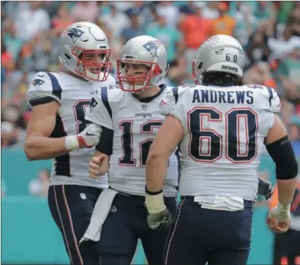  ?? LYNNE SLADKY - THE ASSOCIATED PRESS ?? New England Patriots quarterbac­k Tom Brady (12) is congratula­ted tight end Rob Gronkowski (87) an center David Andrews (60), after throwing a touchdown, during the first half of an NFL football game, Sunday, Dec. 9, 2018, in Miami Gardens, Fla.