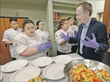  ?? Al Seib Los Angeles Times ?? L.A. UNIFIED’S new Supt. Austin Beutner looks to culinary student Jessica Hernandez before serving food at San Fernando High School on Tuesday as part of his multicampu­s visits across the district.