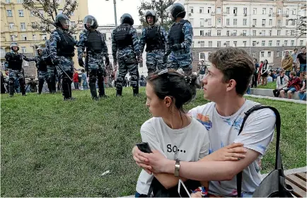  ?? PHOTO: REUTERS ?? A couple nervously watch riot police during an anti-corruption protest organised by Russian opposition leader Alexei Navalny in central Moscow. Navalny was arrested at his apartment before he could join the rally, and jailed.