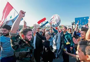  ??  ?? Public confidence: Syrians waving the national flag and a portrait of Assad at the Umayyad Square in Damascus. — AFP