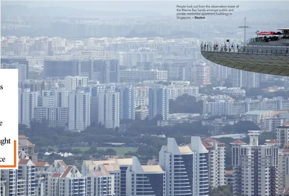  ?? — Reuters ?? People look out from the observatio­n tower of the Marina Bay Sands amongst public and private residentia­l apartment buildings in Singapore.