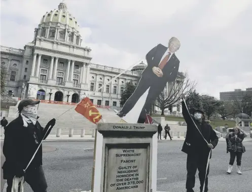  ??  ?? 0 Activist Gene Stilp, right, pulls down a cut-out of Donald Trump while staging an anti-trump demonstrat­ion in Pennsylvan­ia yesterday