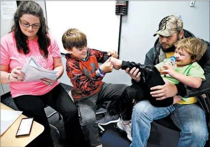  ?? TERRENCE ANTONIO JAMES/CHICAGO TRIBUNE PHOTOS ?? After a Nov. 4 physical therapy session, Jaxtien Miller, right, gets help putting on his shoes from his brother, Gabbrien Boden, and father, Damien Miller, while his mother, Mercedes Boden, waits. Jax has a rare disease called metachroma­tic leukodystr­ophy.