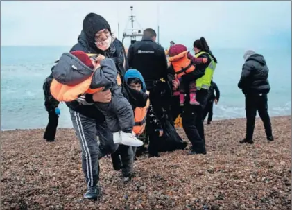  ?? / AFP ?? Una mujer con sus hijos, tras desembarca­r ayer en una playa de Dungeness (Inglaterra).