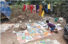  ?? — AFP ?? Dhanosh dries out his school books after flooding his home in Kochi on Tuesday.