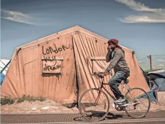  ?? PHILIPPE HUGUEN, AFP/GETTY IMAGES ?? A migrant rides his bicycle inside the camp June 24 in Calais, France. The town’s mayor, Natacha Bouchard, says the camp has left Calais in “complete pain.”