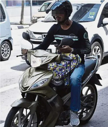  ??  ?? Cause for concern: A motorcycli­st using his mobile phone while on the road.