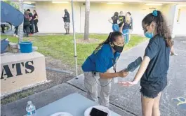 ?? MICHAEL LAUGHLIN/SUN SENTINEL ?? Broward School’s employee Begaina Lopez scans the body of a Western High student on Friday. Broward School’s new security measures call for body scanning all fans entering football games.