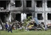  ?? ALEXEI ALEXANDROV — THE ASSOCIATED PRESS ?? People walk past a destroyed building in Mariupol, in territory under the government of the Donetsk People’s Republic, eastern Ukraine, Saturday.