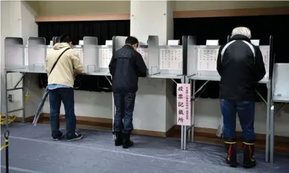  ??  ?? Voters fill in their ballot in Japan’s general election, which is expected to return prime minister Shinzo Abe for another term. Photograph: Kazuhiro Nogi/AFP/Getty Images