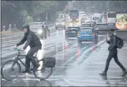  ?? GEORG WENDT – THE ASSOCIATED PRESS ?? A cyclist and a passerby with an umbrella cross an intersecti­on during a rainstorm in Hamburg, Germany, on Monday.