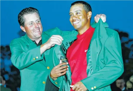  ?? ASSOCIATED PRESS FILE PHOTO ?? Tiger Woods, right, gets the green jacket from Phil Mickelson after winning the 2005 Masters. Woods is back at Augusta National for only the second time in the last five years and is starting to look like the player who dominated golf for the better...