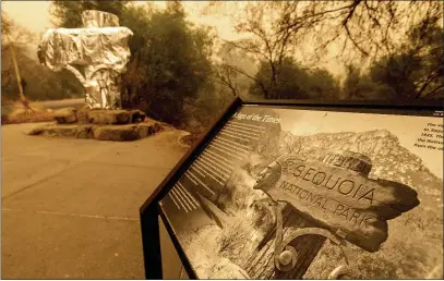  ?? PHOTOS BY NOAH BERGER — THE ASSOCIATED PRESS ?? Fire-resistant wrap covers a historic welcome sign as the KNP Complex Fire burns in Sequoia National Park on Wednesday. The blaze is burning near the Giant Forest, home to more than 2,000giant sequoias.