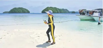  ??  ?? File photo shows a Chinese tourist walking on a beach on the Rock Islands. — AFP photo