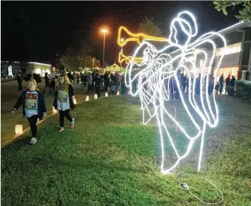  ?? Jason Fochtman ?? Girls walk by the newly light Angels during a previous annual Lighting of the Angels at Shenandoah City Hall on Dec. 1, 2015.