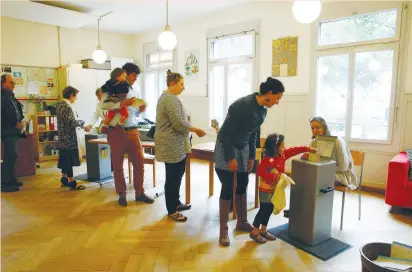  ??  ?? PEOPLE CAST their ballots during a vote on whether to give every adult citizen a basic guaranteed monthly income of 2,500 Swiss francs ($2,560) in a school in Bern yesterday. Opponents, including the government, said the plan would cost too much and...