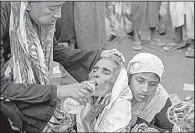  ?? AP/DAR YASIN ?? A Rohingya Muslim woman is given water by a passer-by near the Mushani refugee camp in Bangladesh on Saturday as the woman and her daughter wait for help to reach a doctor.