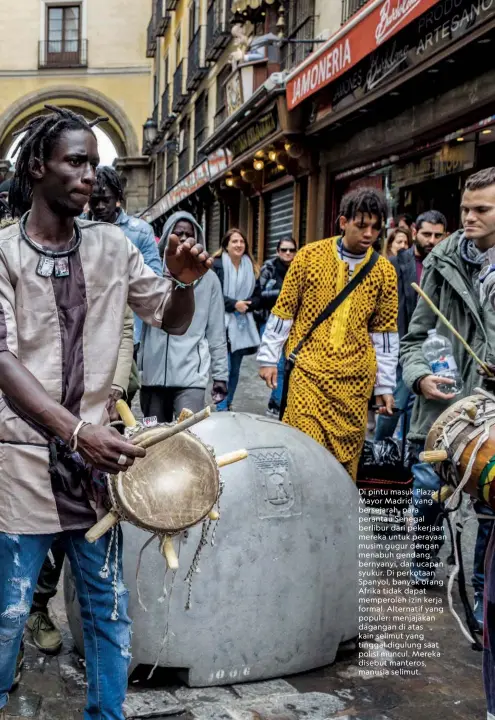  ??  ?? Di pintu masuk Plaza Mayor Madrid yang bersejarah, para perantau Senegal berlibur dari pekerjaan mereka untuk perayaan musim gugur dengan menabuh gendang, bernyanyi, dan ucapan syukur. Di perkotaan Spanyol, banyak orang Afrika tidak dapat memperoleh izin kerja formal. Alternatif yang populer: menjajakan dagangan di atas kain selimut yang tinggal digulung saat polisi muncul. Mereka disebut manteros, manusia selimut.