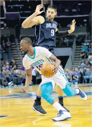  ?? STREETER LECKA/GETTY IMAGES ?? Hornets G Kemba Walker drives past Magic C Nikola Vucevic in the first quarter of Monday night’s game in Charlotte. Walker scored a game-high 29 points as the Hornets beat the Magic for the 9th straight time.