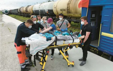  ?? YURIY DYACHYSHYN/GETTY-AFP ?? Medics prepare to transfer a patient from a train to an ambulance Saturday in Lviv, Ukraine.