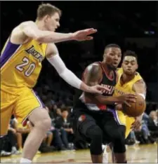  ?? ALEX GALLARDO — THE ASSOCIATED PRESS FILE ?? Portland’s Damian Lillard, center, drives between the Lakers’ Timofey Mozgov (20) and guard D’Angelo Russell, right. Russell, the second pick of the draft just two years ago, and Mozgov were traded to the Nets this week.