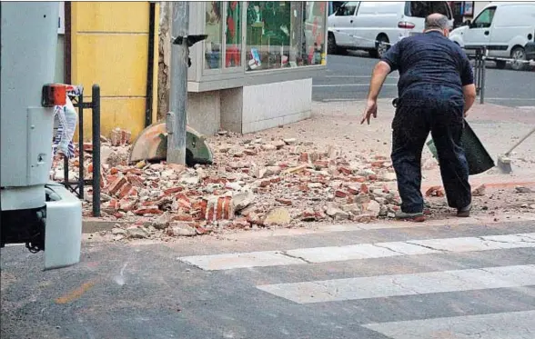  ?? FRANCISCO GARCÍA GUERRERO / EFE ?? Un hombre limpia una caída de escombros de la fachada de un edificio en una calle de Melilla