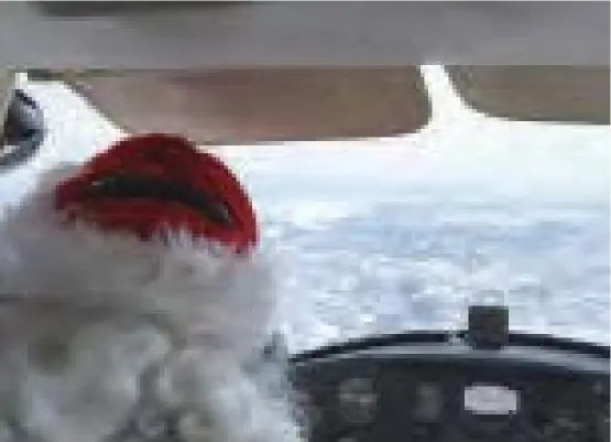  ?? ?? Santa is seen in the pilot's seat of a Cessna airplane, surrounded by an icy, snowy runway area.