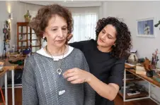  ?? ?? Shah (right) fits a client with one of her eclectic jewellery pieces at her home studio, where she creates eclectic hand-made jewellery crafted using locally sourced raw materials varying among semi-precious stones and metals, in Nairobi.