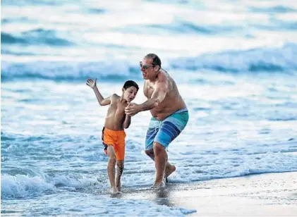  ?? MICHAEL LAUGHLIN/SOUTH FLORIDA SUN SENTINEL ?? Dr. Thomas Sansone plays with his son, Frank, 7, as they enjoy the weather on Dania Beach on Friday. The Sansones are from Rochester, New York, where Friday’s temperatur­e fell to 23 degrees with snow showers.