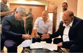  ?? UNITED ARAB LIST ?? Mansour Abbas, right, leader of the United Arab List, signs a new governing coalition agreement with Israel’s opposition leader Yair Lapid, left, and partner Naftali Bennett on Wednesday in Ramat Gan, Israel. The group beat a midnight deadline.