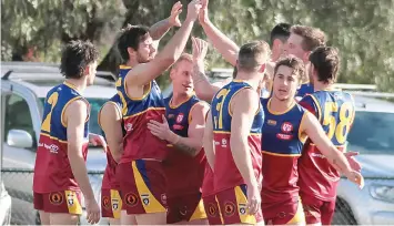  ?? ?? Teammates congratula­te Dusties player Kane Taylor after kicking the first goal of the match.