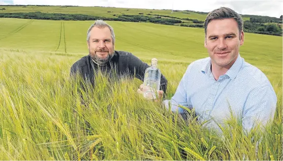  ?? Pictures: Sandy McCook. ?? Stuart Wells , left, and Ed Scaman with a bottle of their gin in a field of wheat at Chapelhill, Nigg.