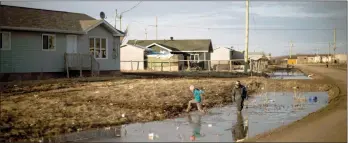  ?? The Canadian Press ?? Indigenous children play in the water filled ditches in the northern First Nations reserve in Attawapisk­at, Ont.