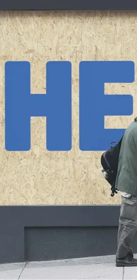  ??  ?? 0 A man walks past a ‘heroes’ tribute to the NHS on the boarded-up