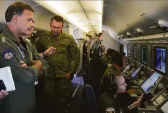  ?? Aaron Favila / Associated Press ?? Adm. John C. Aquilino of the U.S. Indo-Pacific Command (left) looks at videos of Chinese military structures on board a reconnaiss­ance plane flying over islands in the South China Sea.