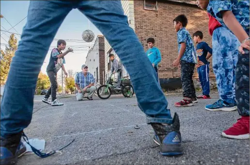  ?? Photos Lori Van Buren / Times Union ?? Tim Doherty, kneeling, watches children play a game outside his West Hill Refugee Welcome Center in Albany on Tuesday. Albany is anticipati­ng the arrivals of roughly 400 refugees in this fiscal year.