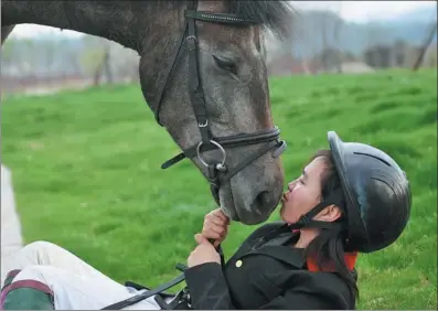  ?? ZHOU MI / XINHUA ?? At an equestrian school in Fuzhou, Jiangxi province, student Tang Siqi is kissing a horse after riding in 2018.