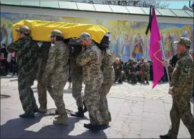  ?? EFREM LUKATSKY — THE ASSOCIATED PRESS ?? Ukrainian soldiers carry a coffin with remains of soldier Ruslan Borovyk killed by the Russian troops in a battle, people stand kneeling in the background, at St. Michael cathedral in Kyiv, Ukraine, on Wednesday.