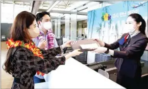  ?? ASIANA AIRLINES ?? An Asiana Airlines official welcomes passengers on a flight bound for Hawaii, one of the first long-haul routes to resume, at the Incheon Airport west of Seoul, on Sunday.