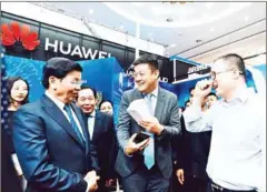  ?? LAO NEWS AGENCY ?? Lao Prime Minister Thongloun Sisoulith (left) and Minister of Post and Telecommun­ications Thansamay Kommasith (behind) at the Huawei booth at the Laos ICT Expo 2019 last week.