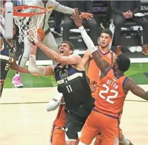  ?? MIKE DE SISTI/MILWAUKEE JOURNAL SENTINEL ?? Brook Lopez squeezes through a pair of Suns defenders and makes a tough shot during the second quarter of Game 6.