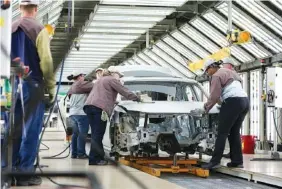  ?? STAFF PHOTO BY ERIN O. SMITH ?? Volkswagen employees work around a car on the assembly line at the Chattanoog­a Volkswagen plant in 2017.