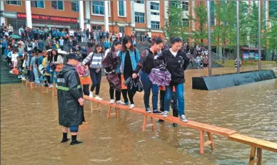  ?? ZHONG XIN / CHINA NEWS SERVICE ?? Students have to walk on benches to stay dry on Liupanshui Normal University campus on Thursday after heavy rainfall caused flooding in Liupanshui, Guizhou province.
